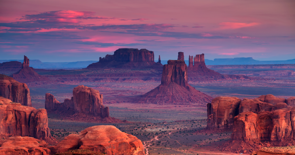 Monument Valley’s sandstone buttes glowing red under the soft light of sunset.